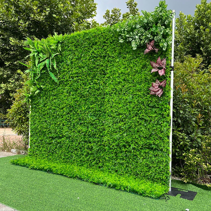 Artificial green wall with decorative plants on a grassy area