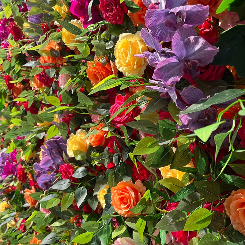Colorful floral arrangement with various silk flowers and green leaves.
