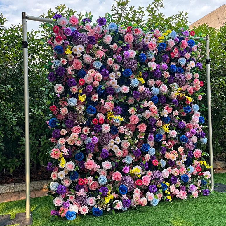 Floral wall made of various flowers on a stand with greenery in the background