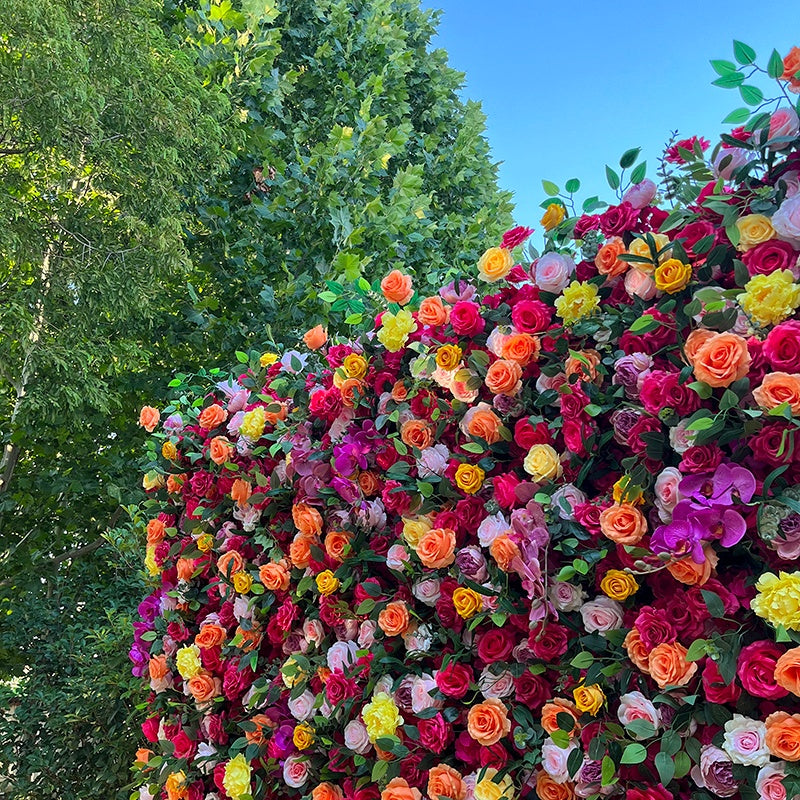 Colorful flower wall with a clear blue sky and green trees in the background